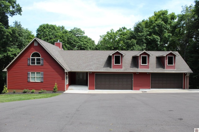 view of front of property featuring aphalt driveway, an attached garage, and roof with shingles
