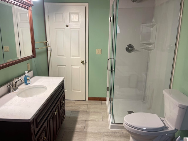 bathroom featuring vanity, toilet, and a shower with door