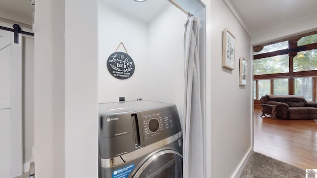 clothes washing area featuring hardwood / wood-style floors and a barn door