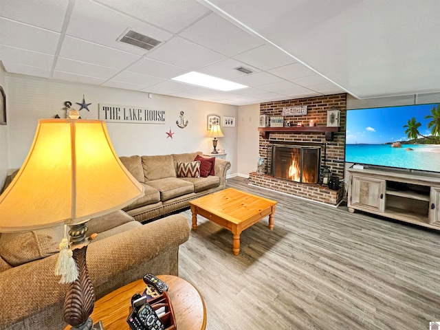 living room featuring hardwood / wood-style flooring, a fireplace, and a paneled ceiling