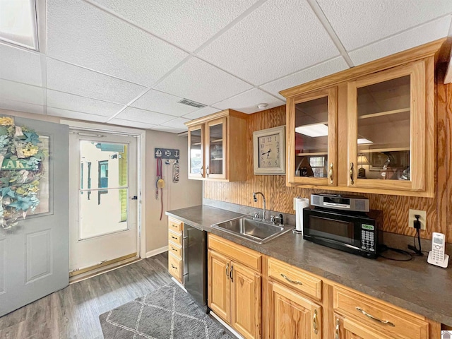 kitchen featuring dark hardwood / wood-style floors, a paneled ceiling, wooden walls, and sink