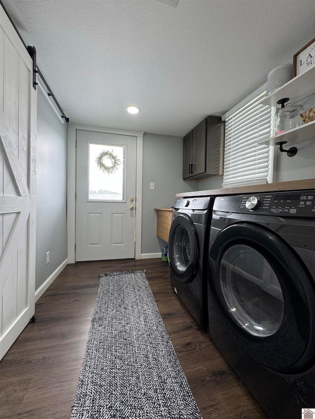 washroom featuring dark hardwood / wood-style flooring, a textured ceiling, a barn door, and washing machine and clothes dryer