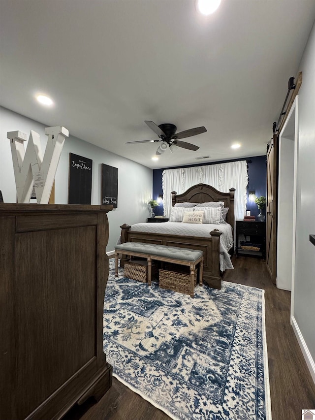 bedroom featuring ceiling fan, dark wood-type flooring, and a barn door