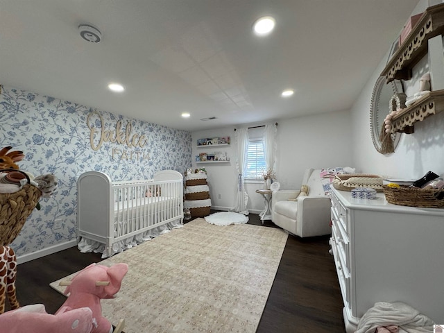 bedroom featuring a crib and dark hardwood / wood-style floors