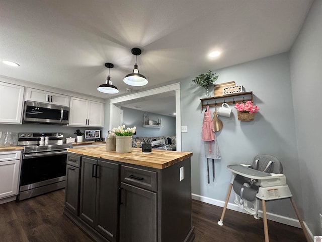 kitchen with stainless steel appliances, white cabinetry, decorative light fixtures, and wooden counters