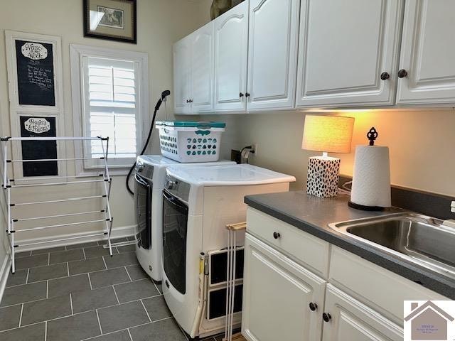 washroom with washer and clothes dryer, cabinets, dark tile patterned flooring, and sink