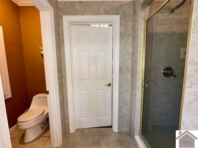 bathroom featuring walk in shower, toilet, and tile patterned floors