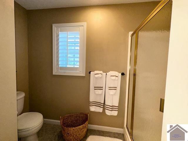 bathroom featuring tile patterned flooring, toilet, and an enclosed shower