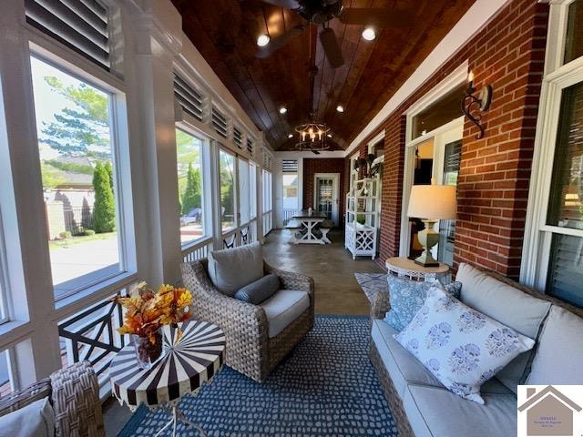 sunroom with wooden ceiling, ceiling fan with notable chandelier, and lofted ceiling