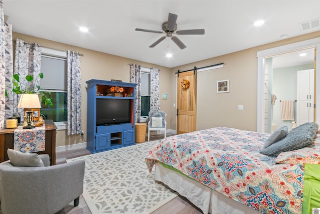 bedroom featuring wood-type flooring, ceiling fan, and a barn door