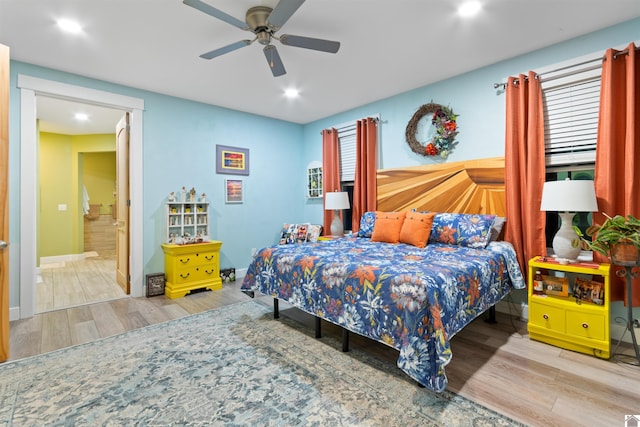 bedroom with hardwood / wood-style floors, ceiling fan, and ensuite bath