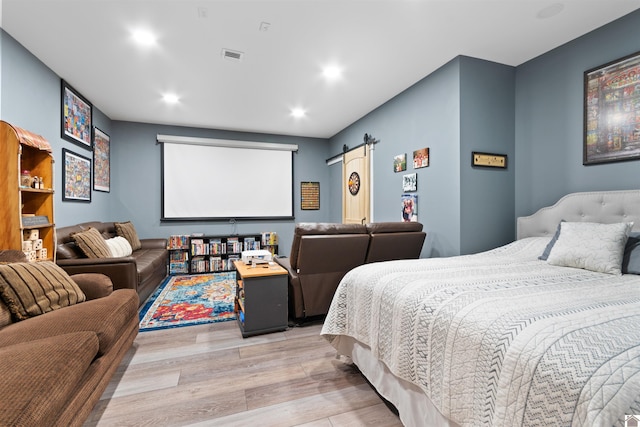 bedroom with hardwood / wood-style floors and a barn door