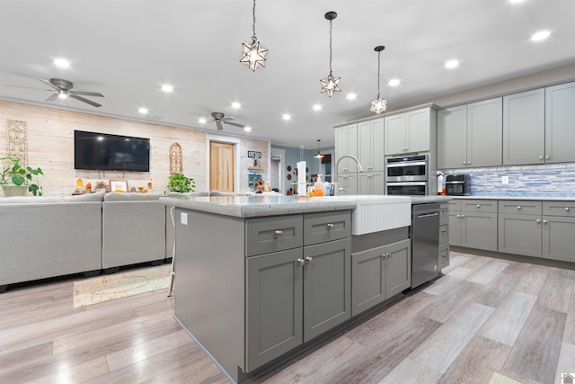 kitchen featuring gray cabinets, appliances with stainless steel finishes, light hardwood / wood-style flooring, and a kitchen island with sink