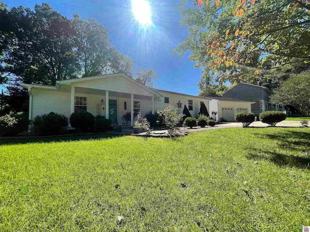 ranch-style home featuring a garage, a front lawn, and covered porch