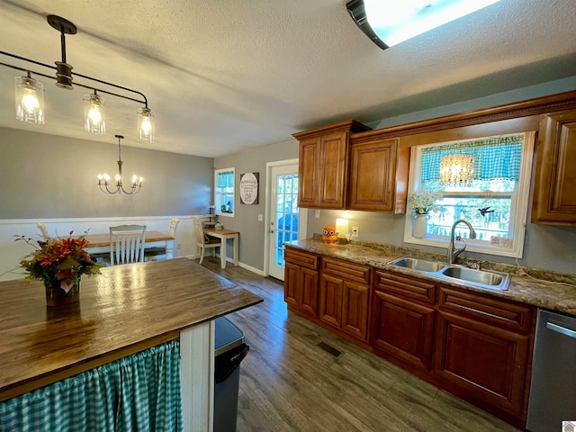 kitchen with a healthy amount of sunlight, hanging light fixtures, sink, and dark wood-type flooring