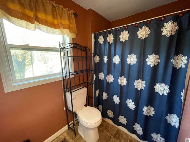 bathroom featuring tile patterned flooring, walk in shower, and toilet