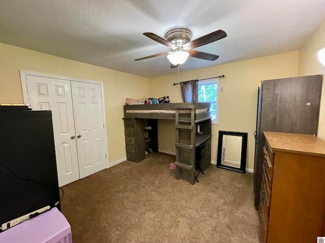 carpeted bedroom featuring a closet, ceiling fan, black refrigerator, and a textured ceiling