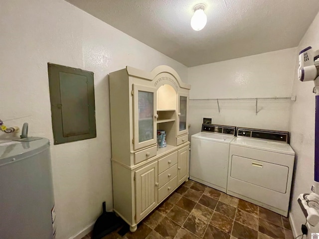 clothes washing area with gas water heater, electric panel, washer and dryer, and a textured ceiling