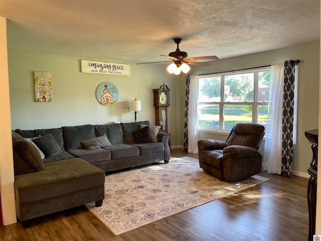 living room featuring ceiling fan, a textured ceiling, and dark hardwood / wood-style flooring