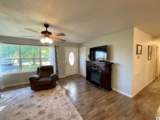 living room featuring a textured ceiling, wood-type flooring, and ceiling fan