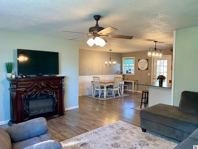 living room with a textured ceiling, ceiling fan with notable chandelier, and hardwood / wood-style floors