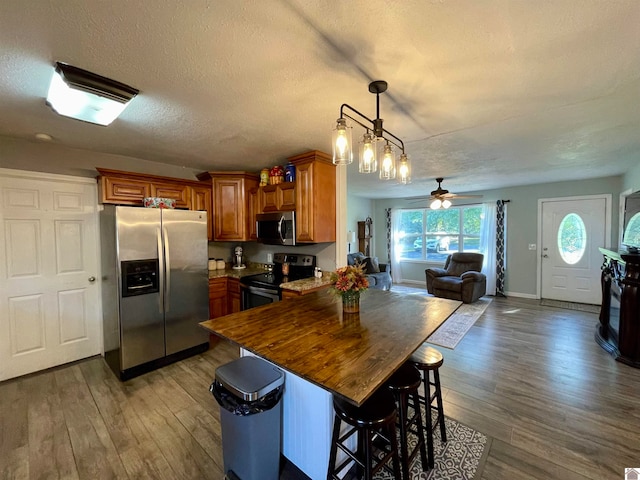 kitchen with appliances with stainless steel finishes, wood-type flooring, and a textured ceiling