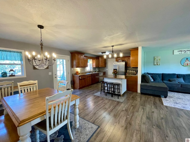 dining room with a notable chandelier, a textured ceiling, dark wood-type flooring, and sink