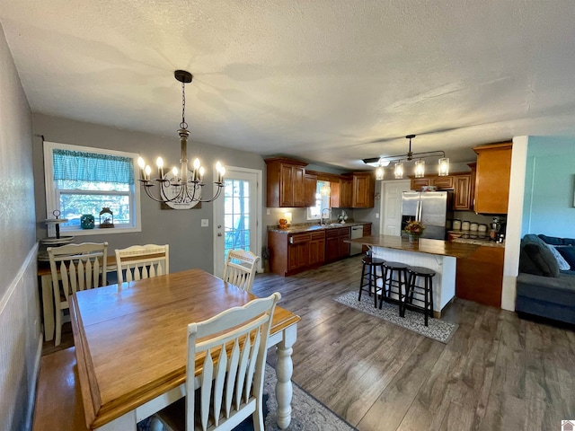 dining room with a textured ceiling, sink, dark wood-type flooring, and a notable chandelier