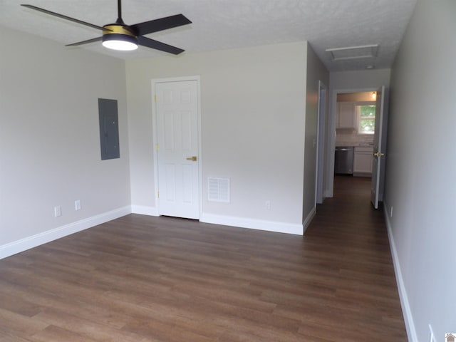 spare room featuring electric panel, ceiling fan, dark wood-type flooring, and a textured ceiling