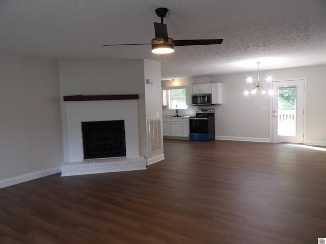 unfurnished living room with sink, dark wood-type flooring, a textured ceiling, and a healthy amount of sunlight