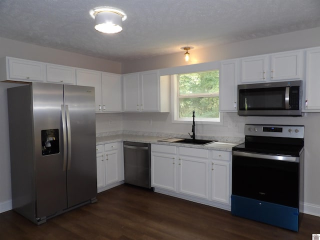 kitchen with stainless steel appliances, sink, dark hardwood / wood-style flooring, white cabinetry, and a textured ceiling