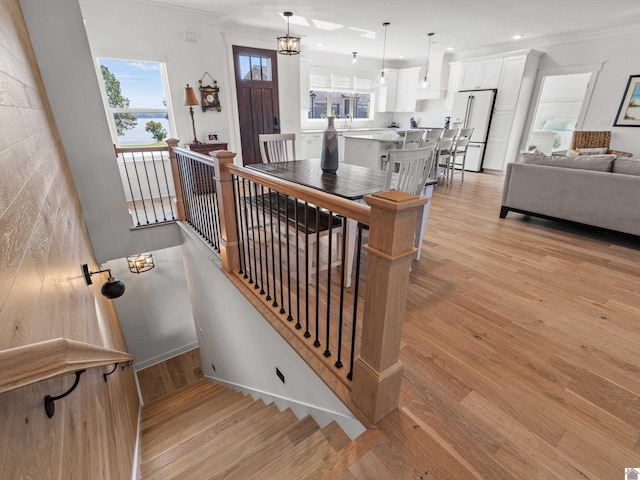 stairway with crown molding, hardwood / wood-style floors, sink, and a notable chandelier