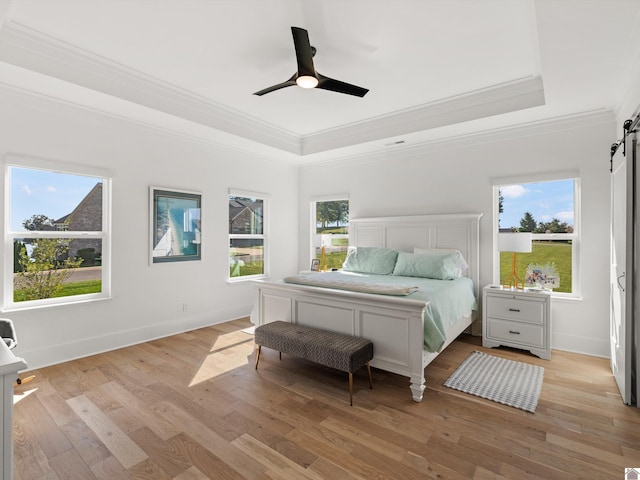 bedroom with light wood-type flooring, a barn door, and multiple windows