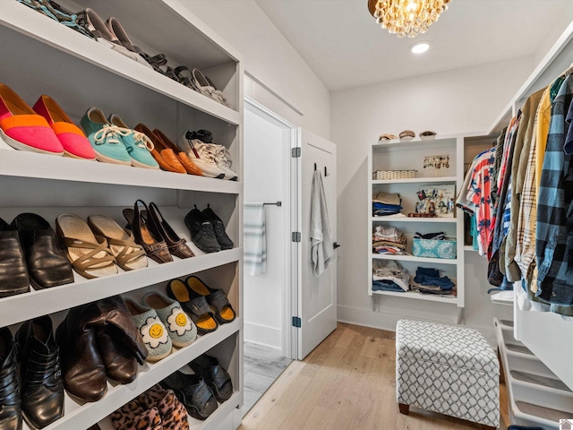 spacious closet featuring a notable chandelier and light hardwood / wood-style floors