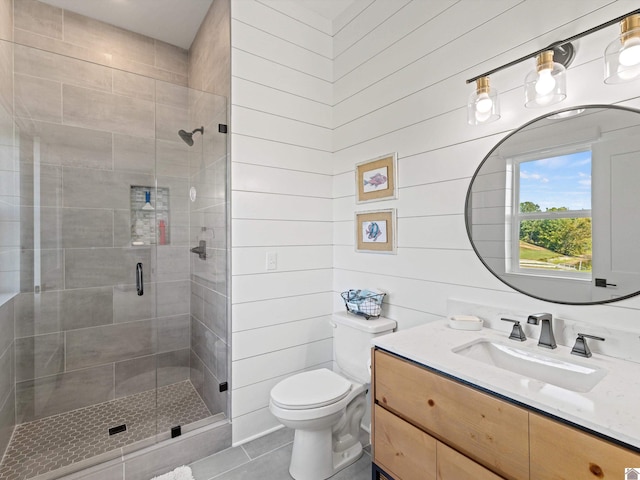 bathroom with vanity, tile patterned flooring, wooden walls, toilet, and an enclosed shower