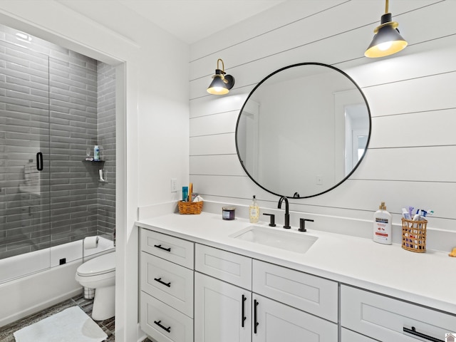 full bathroom featuring wooden walls, combined bath / shower with glass door, vanity, and toilet