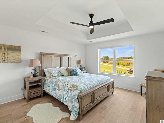 bedroom featuring a tray ceiling, light hardwood / wood-style floors, and ceiling fan