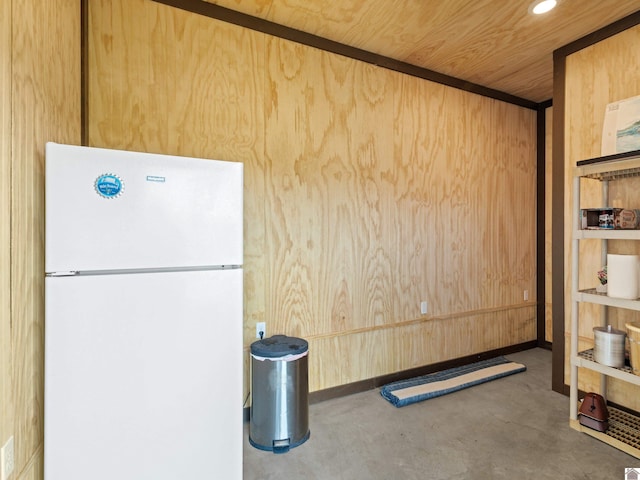 interior space featuring white refrigerator, wood walls, and wooden ceiling