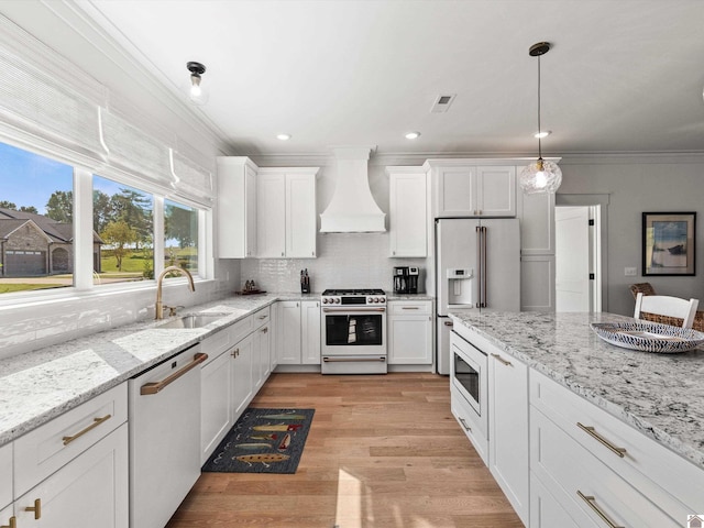 kitchen with sink, white cabinets, custom exhaust hood, light hardwood / wood-style flooring, and stainless steel appliances