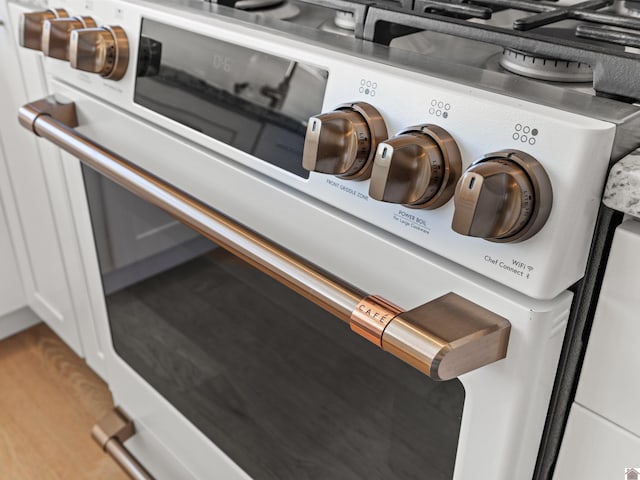 interior details with white cabinetry, stove, and hardwood / wood-style flooring