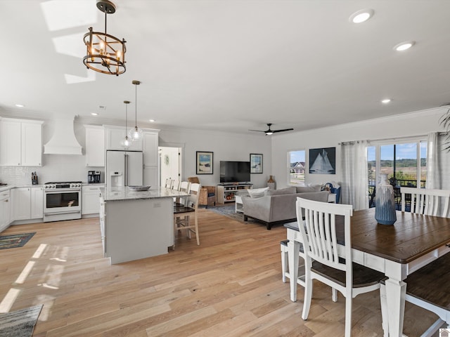 kitchen with custom exhaust hood, hanging light fixtures, white appliances, a kitchen island, and white cabinetry