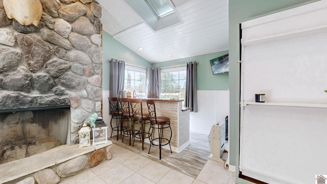 bar featuring a stone fireplace, wood ceiling, lofted ceiling, and light hardwood / wood-style flooring