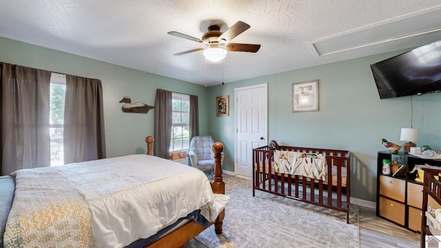 bedroom with light hardwood / wood-style flooring, ceiling fan, and a textured ceiling