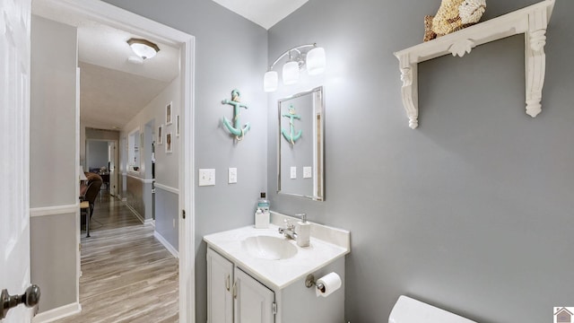 bathroom featuring wood-type flooring, vanity, and toilet