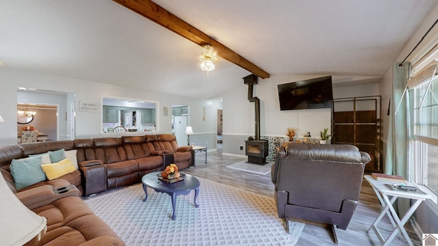 living room featuring vaulted ceiling with beams, hardwood / wood-style flooring, and a wood stove