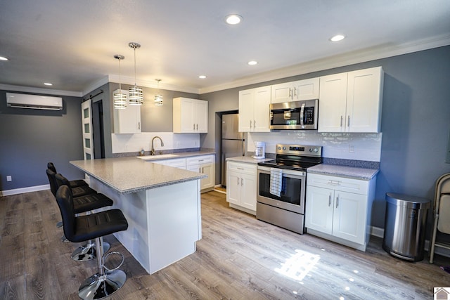 kitchen featuring white cabinets, sink, appliances with stainless steel finishes, light hardwood / wood-style floors, and an AC wall unit