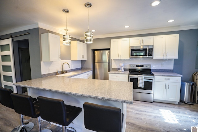 kitchen with light wood-type flooring, sink, white cabinetry, a barn door, and stainless steel appliances