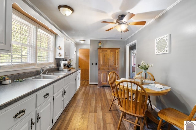 kitchen featuring white cabinets, light hardwood / wood-style flooring, crown molding, and sink