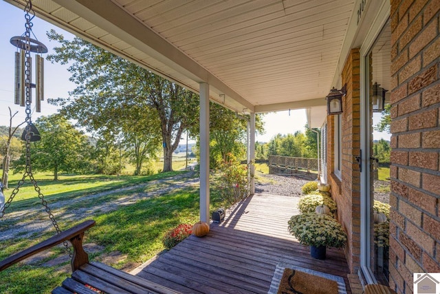 wooden terrace with a lawn and a porch