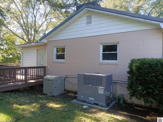 rear view of property featuring a wooden deck, a lawn, and central AC